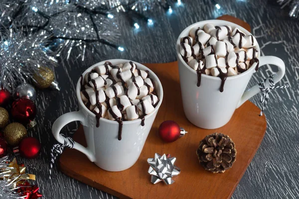 ホットチョコレートまたはマシュマロとココアは クリスマスの装飾が施された2つのマグカップでチョコレートソースに覆われています — ストック写真