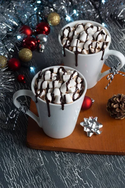 ホットチョコレートまたはマシュマロとココアは クリスマスの装飾が施された2つのマグカップでチョコレートソースに覆われています — ストック写真