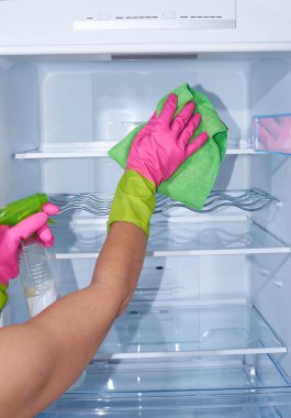 Boş buzdolabını temizlemek - Eldivenli kadın elleri temizlik bezi ve sprey deterjan tutuyor.