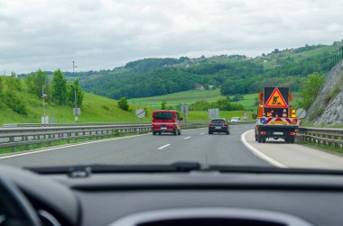 Bir otoyolda giderken bir yol bakım aracının yanından geçmek - arabanın ön camının görüntüsü