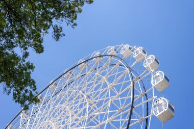 Yazın mavi gökyüzüne karşı beyaz renkli dönme dolap.
