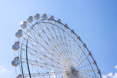 Yazın mavi gökyüzüne karşı beyaz renkli dönme dolap.