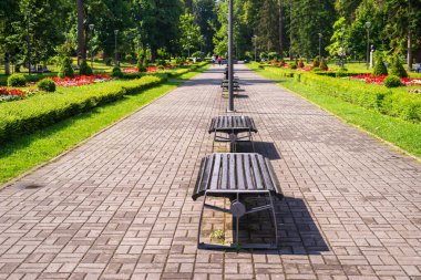 Yazın bankları, yemyeşil çiçekleri, ağaçları ve çalılarıyla halka açık bir park.