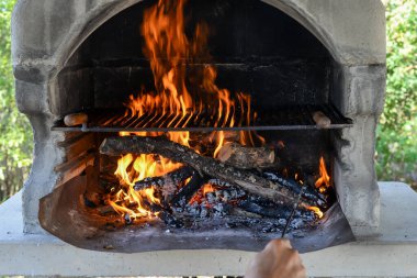 El, şömineyi alevlerle tutuşturur. Boş bir ızgara.