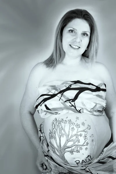 Pregnant woman covered with transparent cloth and tree branches. No copy space