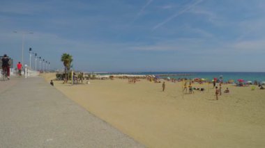 Bu, sadece mayo giymiş 6 çocuğun plaj voleybolu oynadığı gaga görüntüsü. Kumsalda güneşli bir gün ve birçok insan yazın tadını çıkarıyor..