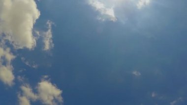 Bu, küçük bulutların birbirinden uzaklaşıp ilerleyişinin görüntüleri. Güneş tepedeyken, çok parlak bir şekilde. Yavaş ilerleyen, mavi gökyüzünde hareket eden beyaz bulutlar..