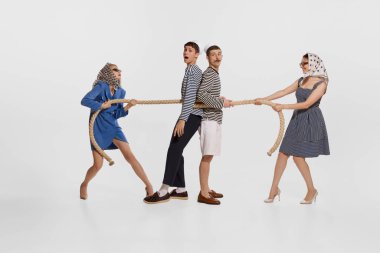 Beyaz arka planda izole edilmiş halatla iki denizciyi bağlayan iki güzel kadının portresi. Seyahat aşkı. Yaz tatili kavramı, işgal, eski moda, klasik tarz. İlan için alanı kopyala