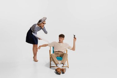 Seyahatte olan genç bir adamın portresi. Çizgili gömlekli bir kadın beyaz arka planda izole edilmiş bir adama tepsi bırakıyor. Tatil kavramı, işgal, eski moda, klasik tarz. İlan için alanı kopyala