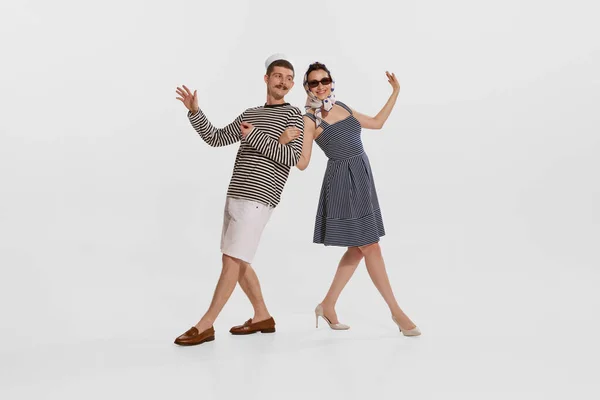 stock image Portrait of young sailor in striped shirt dancing with beautiful young woman isolated over white background. Concept of summer holidays, occupation, retro fashion, vintage style. Copy space for ad