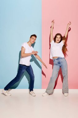 Genç bir çiftin portresi. Mavi-pembe arka planda yalnız dans eden gündelik giysiler içindeki kadın ve erkek. Pozitif olmak. Gençlik kültürü, moda, ilişki, duygu kavramı. İlan için alanı kopyala