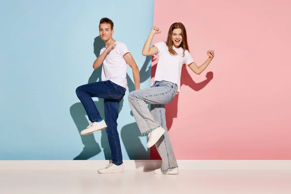 stock image Portrait of young people, man and woman in casual clothes dancing isolated over blue-pink background. Cheerful emotions. Concept of youth, fashion, relationship, facial expression. Copy space for ad