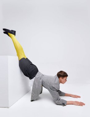 Gri arka planda izole edilmiş ceketli, ceketli ve sarı taytlı şık çocuk portresi. Tuhaf ergen modası. Modern moda kavramı, sanat fotoğrafçılığı, stil, nonoşluk, eşsizlik, reklam