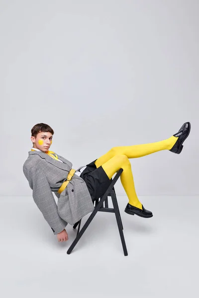 灰色の背景に隔離されたジャケット ブレザー 黄色のタイツに身を包んだスタイリッシュな少年の肖像画 カジュアルで明るい 現代ファッション アート写真 スタイル クィア ユニークさ 広告のコンセプト — ストック写真
