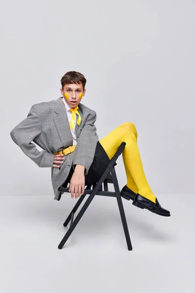 灰色の背景に隔離されたジャケット ブレザー 黄色のタイツに身を包んだスタイリッシュな十代の男の子の肖像画 現代ファッション 現代美術写真 スタイル クィア ユニークさ 広告の概念 — ストック写真