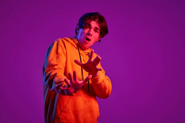 Portret Młodego Mężczyzny Luźnej Bluzie Kapturem Pozującego Fioletowe Tło Neonowym — Zdjęcie stockowe