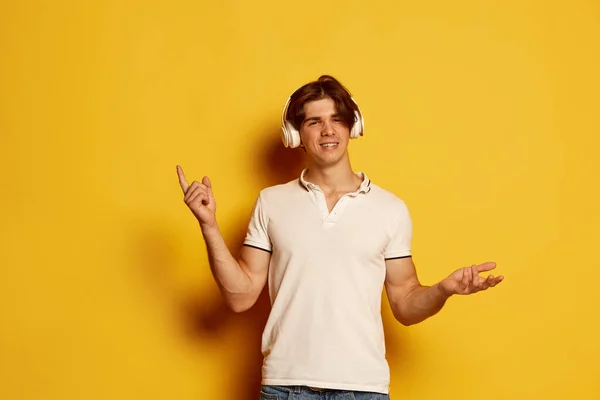 티셔츠를 노란색 배경에 헤드폰을 남성의 온라인 젊음의 일상적 — 스톡 사진