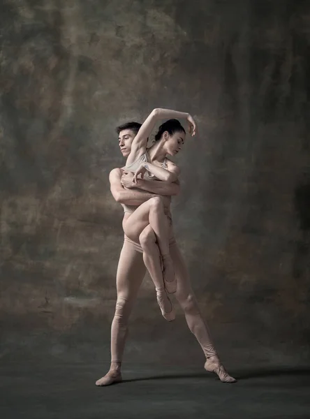 Young man and woman, ballet dancers performing isolated over dark green vintage background. Tender support. Contemporary ballet. Concept of classic dance, artist, beauty. Copy space for ad