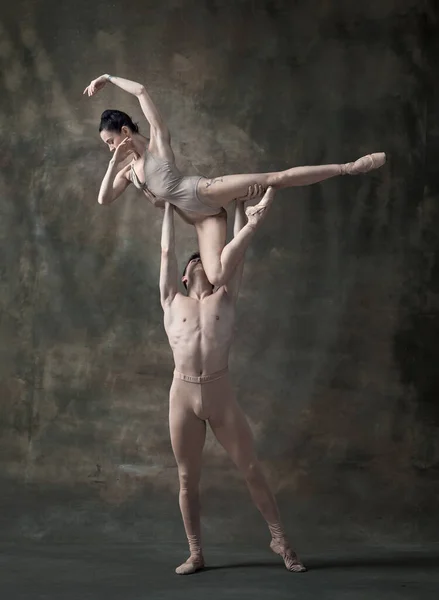Young man and woman, ballet dancers performing isolated over dark green vintage background. Sensuality and elegance. Contemporary ballet. Concept of classic dance, artist, beauty. Copy space for ad