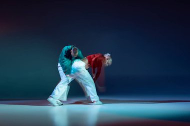 Genç erkek ve kadın portresi, sahnede sahne alan hip-hop dansçıları koyu mavi arka planda karışık ışıklarla izole edilmiş. Hareket kavramı, gençlik kültürü, aktif yaşam tarzı, aksiyon, sokak dansı, reklam