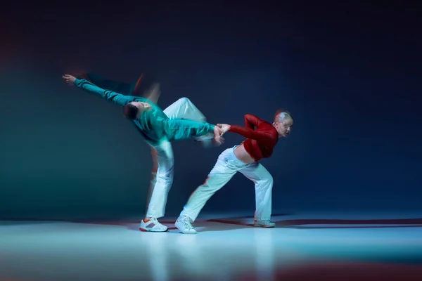 若い男性と女性の肖像は 混合光と濃い青の背景の上に孤立して踊る ヒップホップの演奏 若者文化 アクティブライフスタイル アクション ストリートダンス 広告の概念 — ストック写真