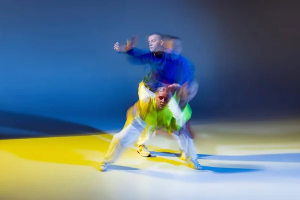 青い黄色の背景に複雑な光で隔離された若い男と女のダンスの肖像画 モダンダンス 若者文化 アクティブライフスタイル アクション ストリートダンス 広告の概念 — ストック写真