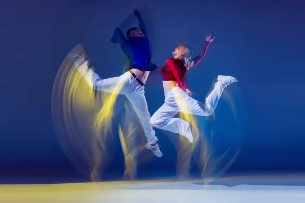 若い男性と女性の肖像は 混合光と濃い青の背景の上に孤立して踊る 自由のジャンプ 若者文化 アクティブライフスタイル アクション ストリートダンス 広告の概念 — ストック写真