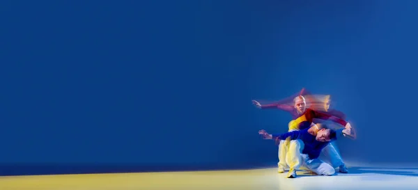 若い男性と女性のダンスの肖像画 ヒップホップの混合照明と濃い青の背景に隔離されたパフォーマンス フライヤー 若者文化 アクティブライフスタイル アクション ストリートダンス 広告の概念 — ストック写真