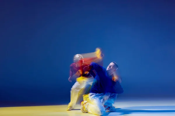 若い男性と女性の肖像は 混合光と濃い青の背景の上に孤立して踊る ヒップホップ 韻を踏んで 若者文化 アクティブライフスタイル アクション ストリートダンス 広告の概念 — ストック写真