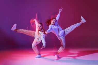 Hip-hop dansı yapan genç kızların portresi, karışık ışıkla karışık menekşe arka planında izole edilmiş düşünce. İfade. Hareket kavramı, gençlik kültürü, aktif yaşam tarzı, aksiyon, sokak dansı