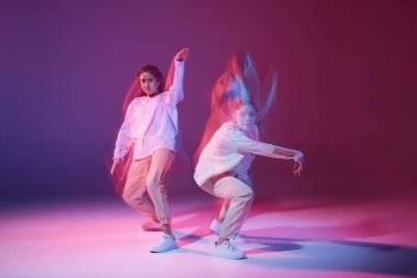 Hip-hop dansı yapan genç kızlar karışık ışıkla karışık menekşe arkaplan üzerinde izole edilmiş. Enerjinin ifadesi. Hareket kavramı, gençlik kültürü, aktif yaşam tarzı, aksiyon, sokak dansı