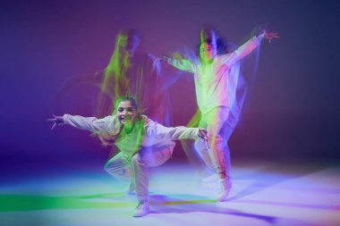 Hip-hop dansı yapan genç kızların portresi karışık ışıkla karışık mavi mor arka planda izole edilmiş. Aktif hobi. Hareket kavramı, gençlik kültürü, aktif yaşam tarzı, aksiyon, sokak dansı