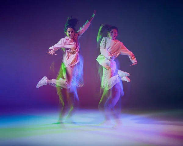 ネオンのグラデーションの青紫色の背景に光が入り混じったヒップホップを踊る少女たちのポートレート 高いジャンプ 若者文化 アクティブライフスタイル アクション ストリートダンスの概念 — ストック写真