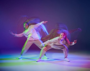 Hip-hop dansı yapan genç kızların portresi karışık ışıkla karışık mavi mor arka planda izole edilmiş. Hobi olarak. Hareket kavramı, gençlik kültürü, aktif yaşam tarzı, aksiyon, sokak dansı