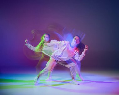Dans eden, hip-hop yapan genç kızların portresi, karışık ışıkla karışık mavi renkli arka planda izole edilmiş. Hareket kavramı, gençlik kültürü, aktif yaşam tarzı, aksiyon, sokak dansı