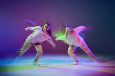Hip-hop dansı yapan genç kızların portresi karışık ışıkla karışık mavi mor arka planda izole edilmiş. Dans kulübü. Hareket kavramı, gençlik kültürü, aktif yaşam tarzı, aksiyon, sokak dansı