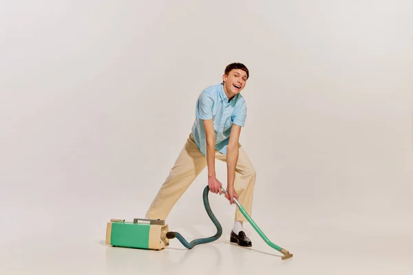 Portret Wesołego Nastolatka Sprzątającego Dom Odkurzaczem Izolowanym Szarym Tle Pojęcie — Zdjęcie stockowe