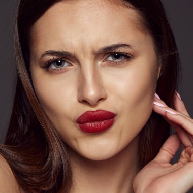 Koyu gri arka planda izole edilmiş kırmızı dudaklı güzel esmer kızın yakın plan portresi. Güzellik, cilt bakımı, kozmetoloji, estetik cerrahi, makyaj, moda, yaşam tarzı kavramı