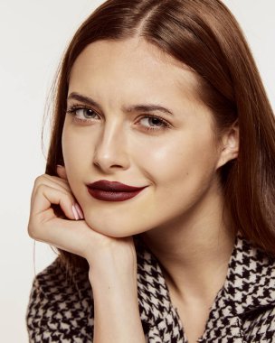 Beyaz arka planda izole edilmiş şık bir ceketle poz veren güzel bir kızın yakın plan portresi. Koyu kırmızı dudak makyajı. Güzellik, cilt bakımı, kozmetoloji, estetik cerrahi, makyaj, moda kavramı