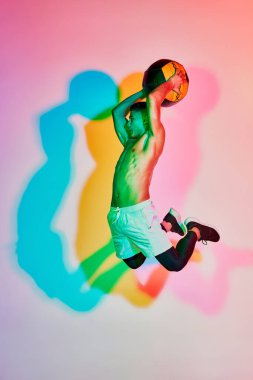 Genç kaslı adam eğitimi, pembe arka planda neon ışıkla izole edilmiş medikal topla zıplama. Çok renkli bir gölge. Spor anlayışı, fitness, sağlıklı ve aktif yaşam tarzı, motivasyon, egzersiz