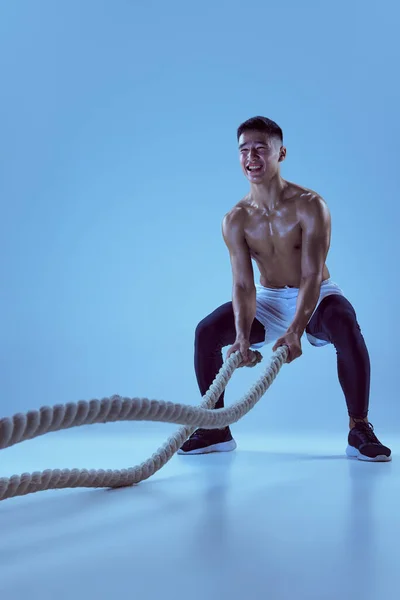 근육질의 남자가 훈련하는 빛으로 밧줄을 잡아당기는 운동을 충분히 건강하고 활동적 — 스톡 사진