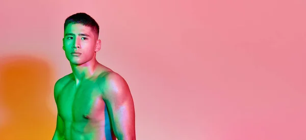 年轻肌肉男训练的肖像 在五彩缤纷的霓虹灯下 在粉色背景上显得孤立无援 健康和积极的生活方式 锻炼的概念 — 图库照片