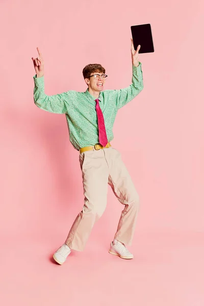 タブレットを使ってる 面白い感情的な男 ヴィンテージスタイルのシャツとズボンを着て学生オタクは 明るいピンクの背景に隔離された楽しみを持っています 楽しさ スタイル ファッション ポジティブで奇妙な感情 — ストック写真