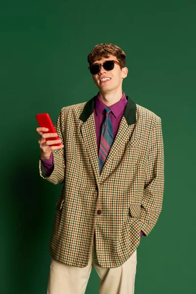 スタジオでは 暗い緑の背景に隔離されたスーツ姿で ヴィンテージファッションスタイルの衣装を着た若い男を撮影します レトロなスタイル 創造性 ファッション ビジネスの概念 — ストック写真