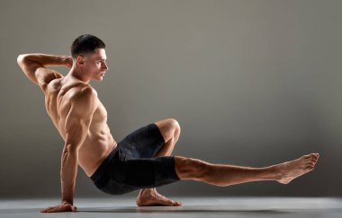 Gri arka planda izole edilmiş hayvan akışı spor unsurları gösteren esnek erkek sporcu portresi. Yoga, fitness, moda sporlar, vücudun güzelliği. İnsan vücudunun zerafeti ve esnekliği