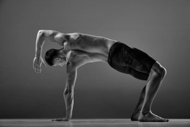 Gri arka planda izole edilmiş hayvan akışı spor unsurları gösteren kaslı erkek sporcunun siyah ve beyaz görüntüleri. Yoga, fitness, moda sporlar, güzellik. İnsan vücudunun zerafeti ve esnekliği