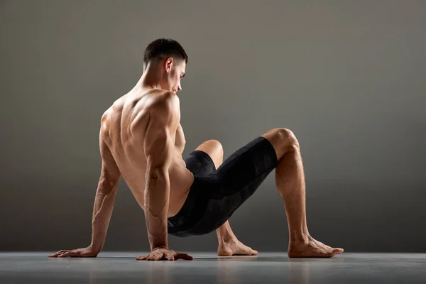 男性柔性肌肉运动员在灰色背景下表现出动物流运动元素的肖像 时髦的运动 美丽的身体 人体的优雅与柔韧 — 图库照片