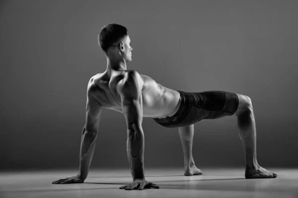 男性弹性肌肉运动员的黑白镜头显示了灰色背景下孤立的动物流运动元素 时髦的运动 人体的优雅与柔韧 — 图库照片