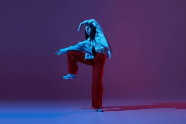Esnek genç kız, dansçı hip-hop dansçısı ya da neonlu koyu mor arka planda izole edilmiş deneysel dans. Çağdaş dans. Müzik, gençlik yaşam tarzı, moda, tarz. İlan için alanı kopyala