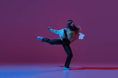 Esnek genç kız, dansçı hip-hop dansçısı ya da neonlu koyu mor arka planda izole edilmiş deneysel dans. Çağdaş dans. Müzik, gençlik yaşam tarzı, moda, tarz. İlan için alanı kopyala